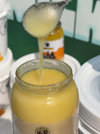 Golden ghee being poured into a glass jar